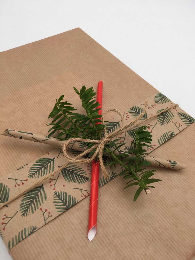 Julklapp i naturfärger med pappersrullar och grön kvist